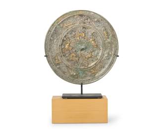 2319
A Chinese silvered and gilt-bronze mirror
Tang Dynasty (618-907 CE) or style
The circular mirror cast with a central knop of a crouching creature surrounded by mythological creatures and birds within vines, set in an enameled metal stand mounted to a wood block base
Mirror: 10.75" Dia; Overall: 16.25" H x 10.75" W x 3.5" D
Estimate: $2,000 - $3,000