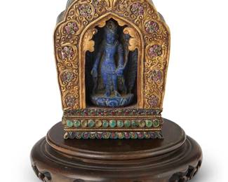 2301
A Tibetan gilt-bronze ga'u shrine with a carved lapis figure of Siddhartha Gautama
Late 19th/20th century
The young Buddha housed inside a carved wood shrine mounted to the front with jeweled gilt-bronze panel, set on a carved wood stand
Shrine: 4.5" H x 3.25" W x 1.75" D; Stand: 1.375" H x 5" Dia.
Estimate: $700 - $900