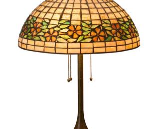 2080
A Unique Art Glass & Metal Company cherry blossom table lamp
Early-20th century
Unmarked
The patinated metal three-light lamp with dished base, surmounted by a leaded glass shade with floral band, electrified
Base: 24" H x 8" Dia.; Shade: 7.125" H x 16.125" Dia.
Estimate: $1,000 - $1,500