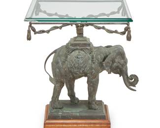 2388
A patinated metal elephant-form side table
20th century
The caparisoned elephant figure issuing four X-form supports wound with metal cording ending in tassels, surmounted by a beveled glass top and raised on a metal and leather-wrapped wood pedestal base
Overall: 25.5" H x 20.25" W x 19.25" D
Estimate: $400 - $600