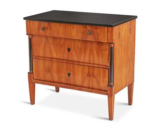 2405
A Biedermeier part-ebonized cherry veneer commode
Circa 1820
The upper drawer with later rounded metal pulls, the lower two locking drawers with ebonized escutcheons, flanked by ebonized columnar accents, surmounted by a later black hardstone top
31" H x 33" W x 18" D
Estimate: $500 - $700