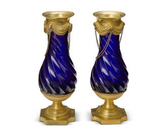 2263
A pair of Louis XVI-style bronze and blue glass vases
19th century
In the manner of Le Creusot, Paris, each glass with a twisted swirling form, mounted with an upper festooned gilt-bronze piece issuing swags of chains, and a lower tiered foot with an architectural square base with scooped corners
2 pieces
Each: 7.25" H x 2.625" Dia.
Estimate: $700 - $900