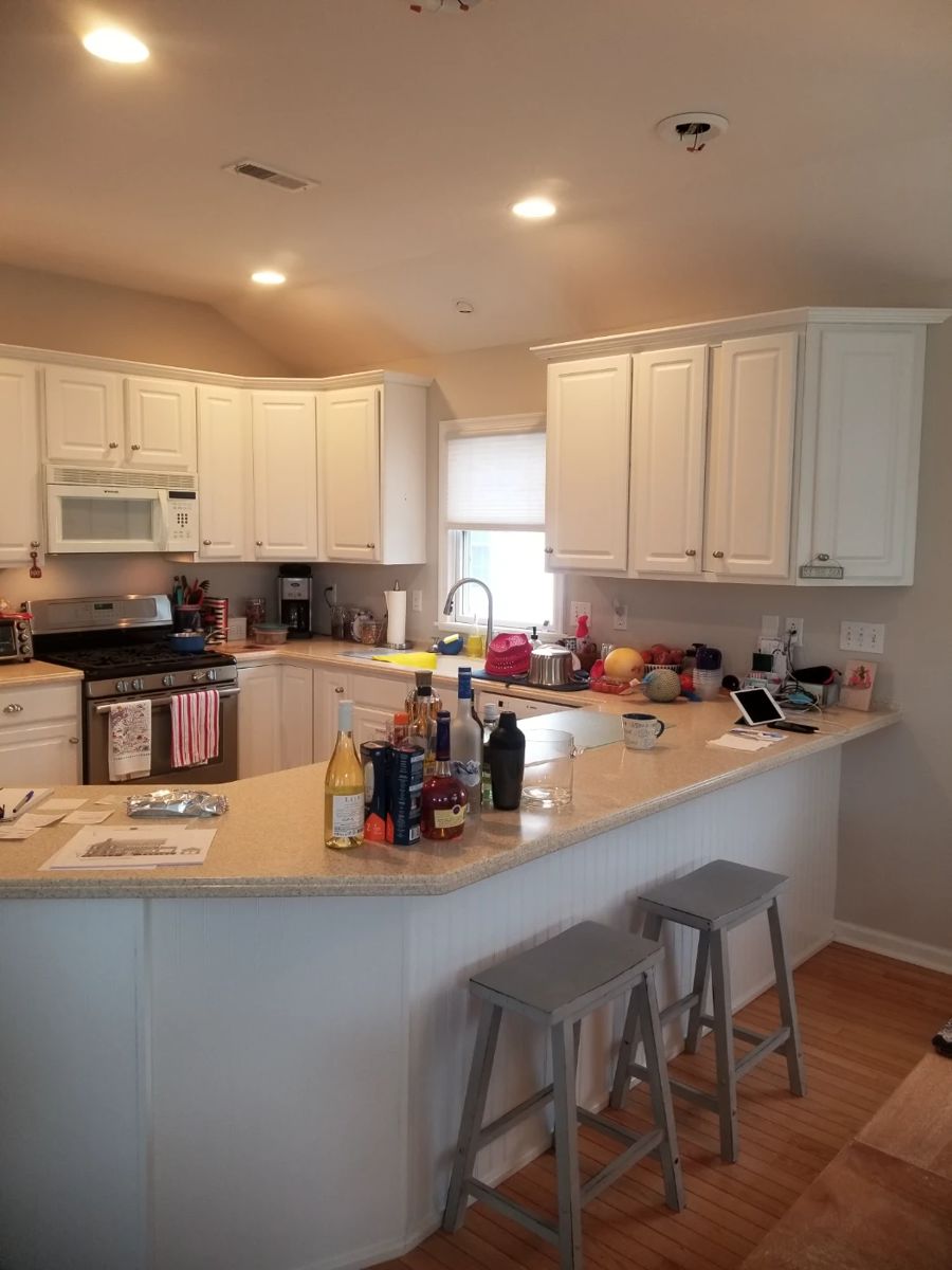Crisp white C-shaped kitchen; two bar stools