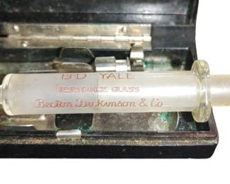 Vintage glass syringe and plunger with two needles and an original bakelite box