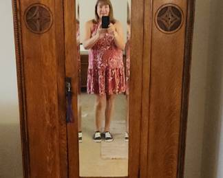 Lovely antique engraved wood wardrobe with mirror, metal rod, and two shelves.