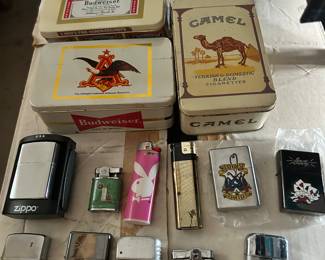 Various cigarette lighters including Zippo,Sailor Jerry, Ronson, Bowers, Bic… in two Bud tins and one Camel tin.