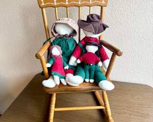 Vintage Wooden Rocking Chair with Decorative Floral Design Holding Four Small Cloth Dolls with Names Sewn on