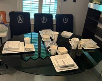 Black glass dining room table with 4 chairs with Paris themed place settings