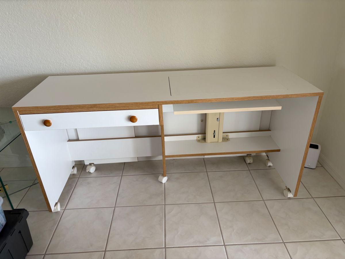 Horn Sewing Cabinet with manual hydraulic lift and on wheels. Measures 60” X 19 1/2”   Has back extension that fold up. With fold up extension 60” X 39”