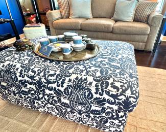 Stylish Living Room with Patterned Ottoman, Beige Sofa, and Chic Tea Set Display