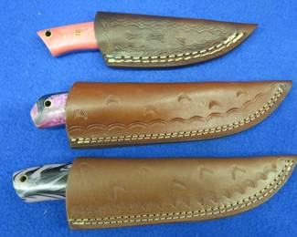 Lot 319. Three new knives with leather sheaths, two are Damascus, none have makers marks