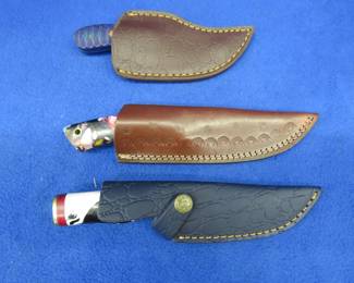 Lot 334. Three new fixed-blade knives with leather sheaths, two are Damascus, no maker's mark