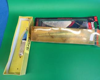 Lot 313. NIP Dominion 4" Sail Fish. Little Doctor 275 spoon in the correct box. Rebel 5 1/4" Spoonbill Minnow in a box in poor condition.