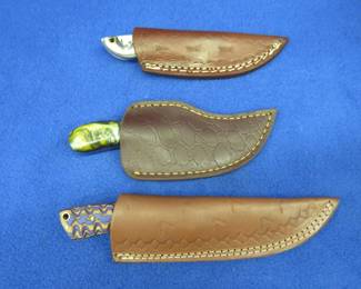 Lot 316. Three new knives with decorative scales and leather sheaths with no maker's mark found on them
