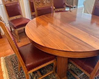(2) Round mahogany dining table with 5 legs, 3 additional leaves. Legs have carved 3" base and 3-1/2" skirt has 1/2" beaded decoration. Circa 1890. 54"d 29"h , leaves 12"d. (3) Set of 6 high-back oak dining room chairs and one matching arm chair. Chairs have Lion or Northwind Face in center, leaf ears, claw feet, upholstered back and seat. Chairs 42-12/"h, arm chaira 45"h.