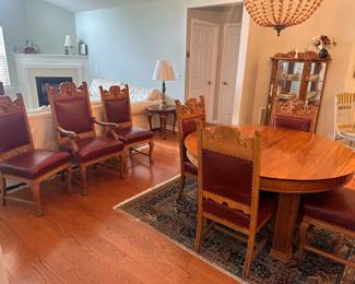(2) Round mahogany dining table with 5 legs, 3 additional leaves. Legs have carved 3" base and 3-1/2" skirt has 1/2" beaded decoration. Circa 1890. 54"d 29"h , leaves 12"d. $2,800 table. Chairs are #(3) Set of 6 high-back oak dining room chairs and one matching arm chair. Chairs have Lion or Northwind Face in center, leaf ears, claw feet, upholstered back and seat. Chairs 42-12/"h, armchair 45"h. Chairs $4,200