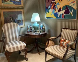 Corner of living room with Sheraton style stripped armchair, leather-top drum table, Celadon lamp, Intricately carved lionhead knees of chair with hairy carved feet, Original art