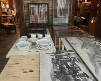 Dishes, artwork, and wooden workbench tables.