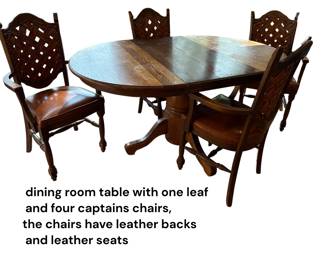 Dining room table with one leaf and four captain's chairs, the chairs have leather backs and leather seats
