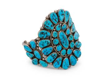 42
A Roanhorse Navajo sterling silver and turquoise cuff bracelet
Late 20th/21st century, Diné
Stamped: Roanhorse / Sterling / 925 [likely for Henry Roanhorse or Calinda Roanhorse-Bowling]
A sterling three-wire cuff with a large cluster-set plaque featuring sawtooth bezel-set turquoise
7" total inner C x 3" H, with a 1.375" gap
103.0 grams gross
Estimate: $400 - $600
