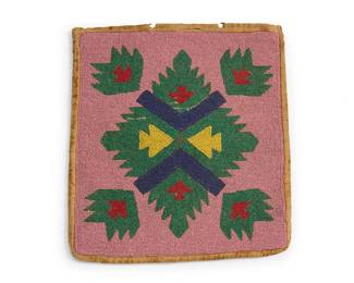 289
A Plateau beaded bag
Early/mid-20th century; Northwest United States/Canada
The single-faced multicolored rectangular bag with the front featuring geometric diamond and arrow motifs worked in beads of blue, green, yellow, and red on a dusty pink field, with a single hide lacing strap, and with velvet edge binding, a velvet back, and pink cotton plaid lining
12" H x 10.75" W
Estimate: $300 - $500
