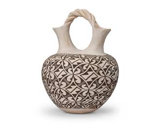 280
Grace Chino (1929-1994, Acoma Pueblo)
A black on white pottery wedding vase, circa 1984
Signed to underside: Grace Chino / Acoma N. Mex
The vase with a rounded body, featuring flared spouts joined by a twist arched handle, with an overall pattern of interlocking lozenge motifs forming four-part circles and stylized floriform motifs
10.5" H x 7.75" Dia.
Estimate: $500 - $700