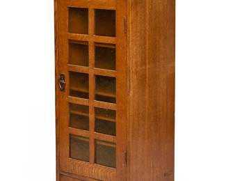 87
A Gustav Stickley music cabinet, no. 70
Circa 1912-1916; Eastwood, NY
With Stickley shop mark [joiner's compass]
The oak wood cabinet of mortise and tenon construction with splined panels, featuring an upper gallery above a single cabinet door with "hammered" amber glass panes between the mullions, with copper pull and lock escutcheon, revealing five adjustable shelves mounted on pegs
47.25" H x 20.25" W x 16.5" D
Estimate: $700 - $900