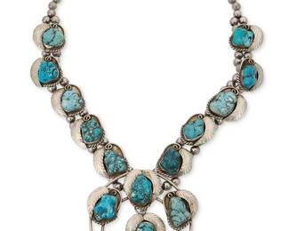 315
A Southwest-style squash blossom necklace
Mid/late 20th century
Unmarked
Featuring a large silver-toned metal two-wire naja with five chunky set turquoise-colored stone plaques and one dangle, each with silver-tone metal feather motif overlay and with ten matching chunky stone set "blossoms", all suspended from two strands of silver-toned beads
24" L x 3.25" H
255.5 grams gross
Estimate: $400 - $600