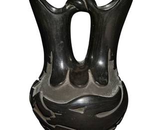 1
Reycita Cosen (1927-2012, Santa Clara Pueblo)
A blackware pottery wedding vase, 1989
Signed and dated to underside: Reycita Cosen / Santa Clara / 6-20-89
The stone-polished black vase featuring flared spouts joined by a twisted arched handle, with a deeply carved Avanyu water serpent motif to body
8.25" H x 5.625" Dia.
Estimate: $200 - $400