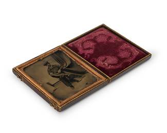 235
A 19th century tintype of a seated man
A tintype depicting a seated man with a curtain to his left, with a chased gold-toned metal preserver within a magenta velvet-lined tooled leather case
Sight: 3" H x 2.5" W
Estimate: $200 - $300