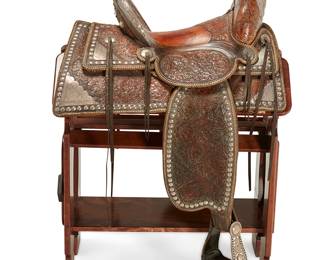 95
A Brydon Bros. silver-mounted parade saddle
Early 20th century
Embossed to seat: Brydon Bros. / Makers / Los Angeles / CA; the gullet inscribed 'Los Prietos Ranch'
The saddle of tooled brown leather with silver-mounted swell and horn, conchos and studs along rear housing skirt and fender, with high back and sheepskin padding, seat size 16, together with a wood saddle stand bearing the D Arrow brand
Seat: 16"; Swell width: 13.5"; Gullet width: 6"; Stand: 31" H x 18" W x 30" D
Estimate: $2,500 - $3,500