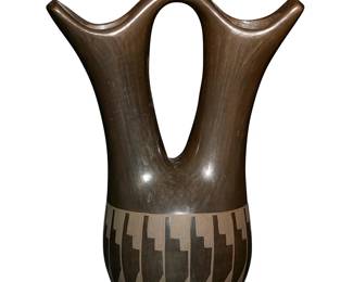 2
Nicolasa Naranjo & Roberta Naranjo (1907-2002 & b. 1946, Santa Clara Pueblo)
A blackware pottery wedding vase, late 20th century
Signed to underside: Nicolasa + Roberta / Santa Clara
The stone-polished black on black vase featuring flared spouts joined by an arched handle, with a band of feathers to rounded body
10" H x 7.25" W x 4.25" D approximately
Estimate: $200 - $400