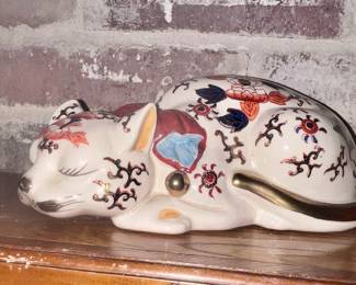 Japanese porcelain figurine of a sleeping cat, known as a "Nemuri Neko" (sleeping cat). 