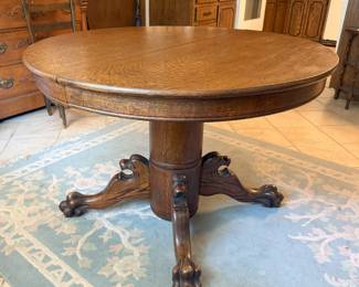 This antique quartersawn oak pedestal round table has characteristic carvings on the legs/feet. It comes with two leaves, to expand into an oval table.