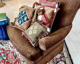 CLUB CHAIR FULL OF BEAUTIFUL CUSTOM PILLOWS.
