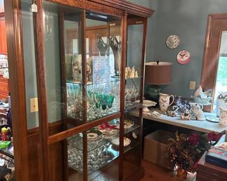 R3 - $225. Howard Miller Lighted Display Cabinet.  Door slides across the front and has a key to lock. Measures 42" at the widest point x 15" deep x 80.5" tall. 