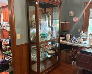 R3 - $225. Howard Miller Lighted Display Cabinet.  Door slides across the front and has a key to lock. Measures 42" at the widest point x 15" deep x 80.5" tall. 