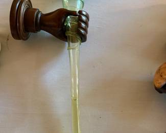Carved hand shelf holding opalescent fluted vase