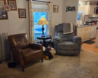 Gray Lazy-Boy Style recliner - in good condition. Purchased 2-3 years ago. Brown leather side chair (x2). Wooden side table. Lamp. Wall decor. 