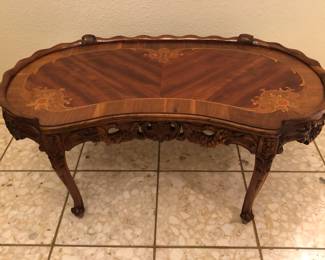 Carved wood kidney shaped coffee table with intricate wood inlay.