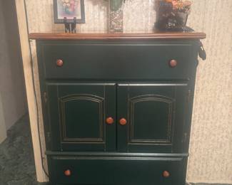 Green and wood chest of drawers, picture on easel, flower arrangement and Halloween decor