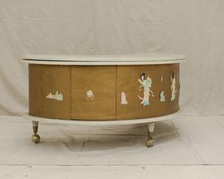 Another view of the "Grand Server" mid-century modern boomerang/kidney shaped coffee table with collapsible bar cabinet, manufactured by A.H. Stock Manufacturing Company. This design was showcased at the 1964 World’s Fair in New York City as an example of American modern furniture. With two external shelves, locking side cabinet doors and resting on legs with casters, this table’s white laminate top swings open to reveal an inside compartment with a mechanical tray: just pull up on the brass handles which lock the tray into place at table height. Wrapped with textured gold vinyl on the sides, with applied mother of pearl pieces in Asian decorative motif.