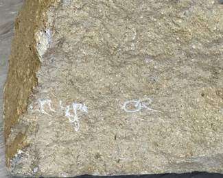 Closeup of artist signature on the striking abstract carved limestone and inset glass sculpture, signed; 52 inches tall