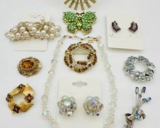 Bright sparkly vintage costume jewelry including a green rhinestone/crystal butterfly, a faceted crystal necklace with AB crystal cluster earrings, a lovely silver tone and blue rhinestone "cat tails" brooch, and more