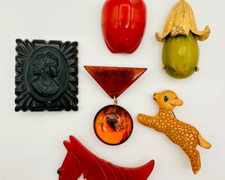 Vintage Bakelite brooches including a leaping lamb, a red apple, and a red Scottish Terrier dog