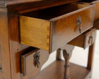Closeup view of the front drawers open in the Welsh dresser, 2 parts: the dresser base has an open pot board and 5 drawers (two wide and three small); the dresser top has cornice top with front scalloped edge and two fixed shelves (or plate groove) for displaying dishware. Replacement pulls. The style dates back to the early 1600s.