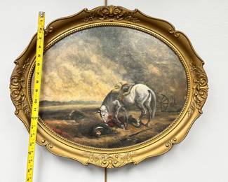 Framed oval painting of battlefield scene with wounded soldier lying in grassy field beneath storm clouds while his saddled white horse stands near him