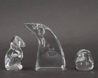 A group of American art glass that displays eloquent artistic renditions of our faithful friends. Puppy Love Hand Cooler No. 8524 designed by Lloyd Atkins and introduced in 1986, a snuggling pair that reflects the cozy comfort of companionship and love. The Dog Hand Cooler No. 8939 sits alertly, while the largest figurine Good Dog No. 8641, designed by David Dowler, conveys affectionate attention in a graceful abstract form. Each is signed “Steuben" to the base. Sizes: Puppy Love 2 3/4 inches L x 1 1/2 inches W x 1 3/4 inchesH, the Dog Hand Cooler 1 3/4 inches L x 3 1/4 inches H, and Good Dog is 3 3/4 inches L x 2 1/4 inches W x 4 1/2 inches H.