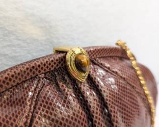 Closeup of Judith Leiber vintage brown snakeskin clutch bag with tigers eye clasp and gold tone chain shoulder strap