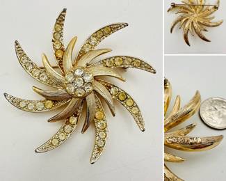 A vintage Sarah Coventry gold tone and crystal rhinestone starburst or pinwheel brooch